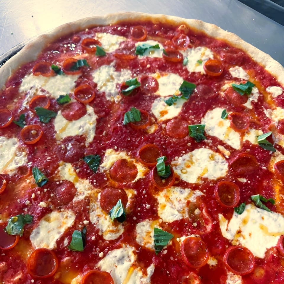Close-up of a Jace's Place pepperoni pizza with fresh basil and melted mozzarella cheese.