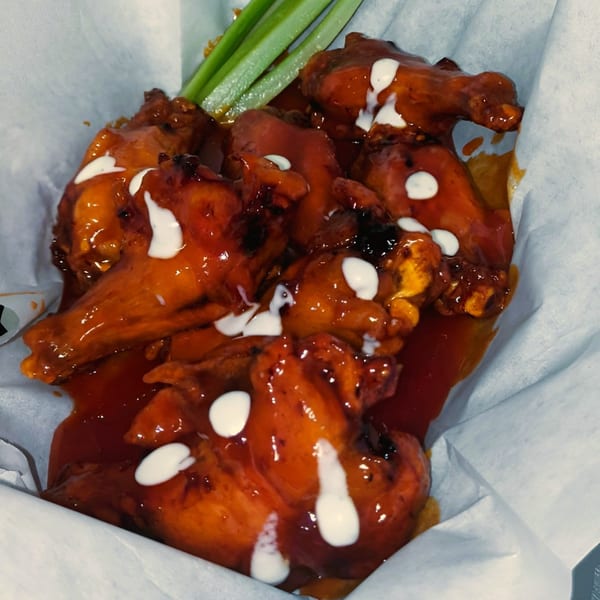 Jace's Place buffalo wings with ranch drizzle and celery sticks in a white paper-lined basket.