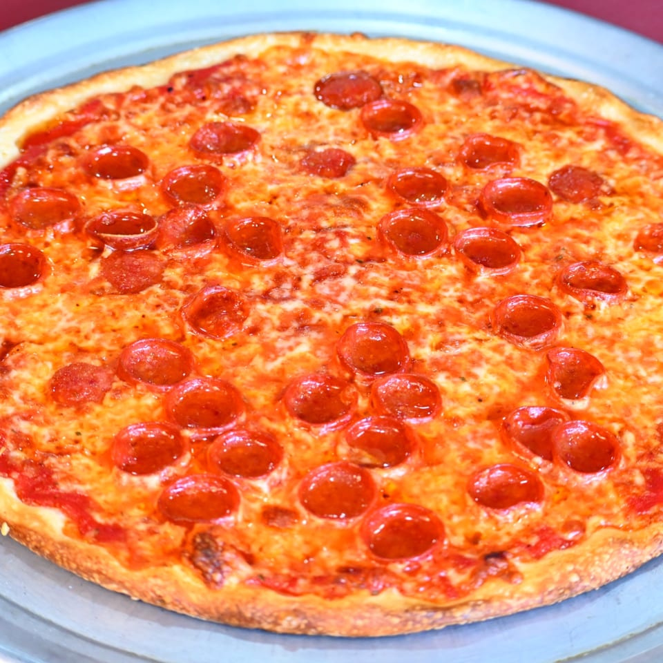 Pepperoni pizza with melted cheese and a golden crust on a blue plate.